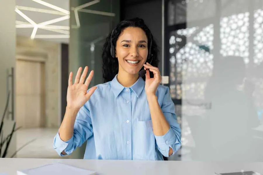 A DICHIR team member on a call, smiling and waving