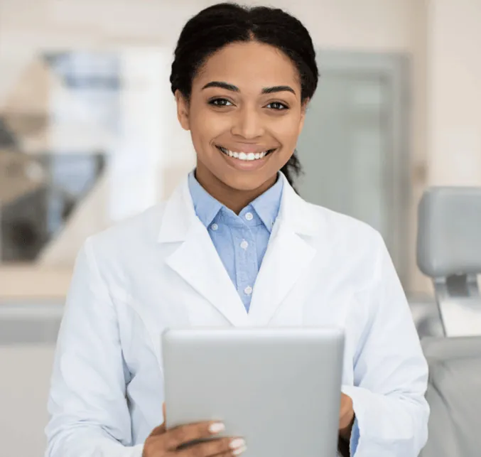 A smiling clinician in a white coat holding a tablet